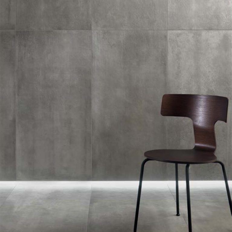 Urbana 24x24 Grigio concrete-look porcelain tile on the wall and floor with a dark chair