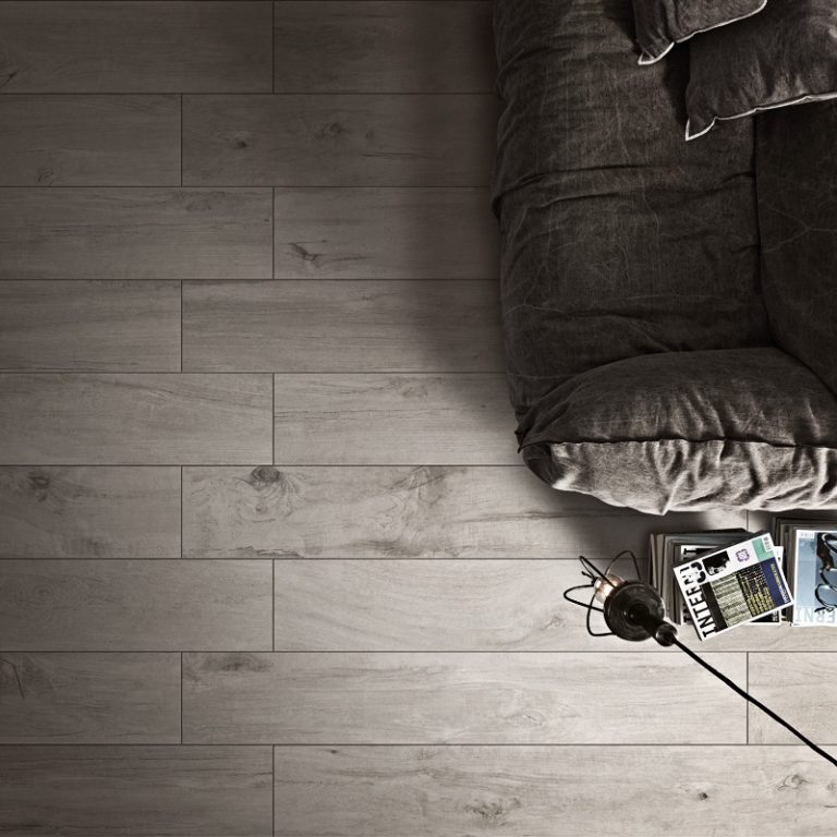 Overhead view of a Colville 8x48 Gray wood-look porcelain tile floor beside a sofa