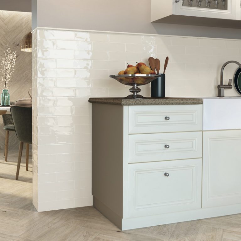 Kitchen with Ravello 3x12 White glossy wall tile on a partition wall and white cabinets