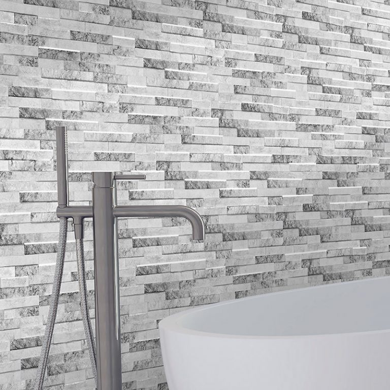 Close-up of Natura Artico stone-look interlocking porcelain wall panels behind a floor-mount tub faucet