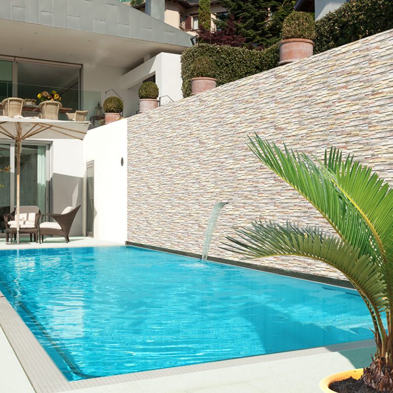 Pool terrace wall in Natura Tropical stone-look interlocking porcelain wall panels with a spout fountain