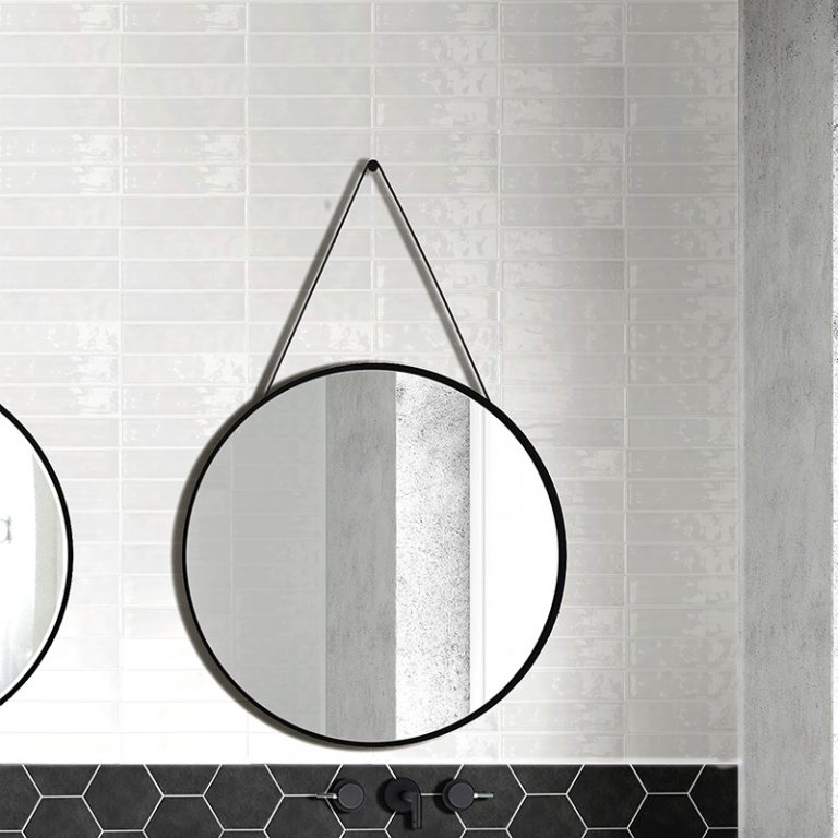 Colors White brick wall tile with a Colors Black hexagon tile band behind a round strap mirror