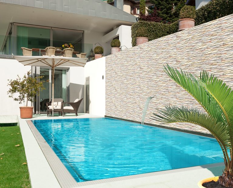 Pool with a garden wall clad in Natura Tropical stone-look interlocking porcelain wall panels