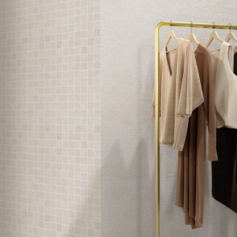 Boutique wall in Silky Stone Greige 24x48 porcelain tile and 2x2 square mosaic behind a clothing rack