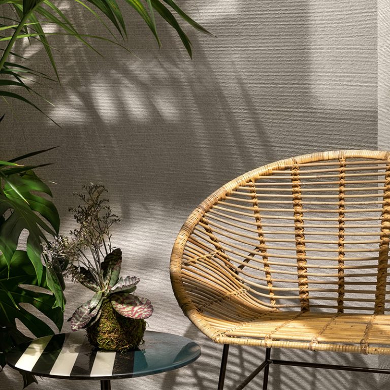 Silky Stone Light 24x48 porcelain wall tile behind a rattan chair and plants