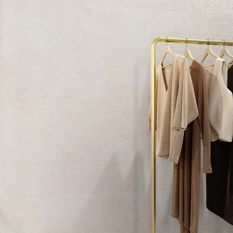 Shop wall in Silky Stone Light 24x48 porcelain tile behind a brass clothing rack