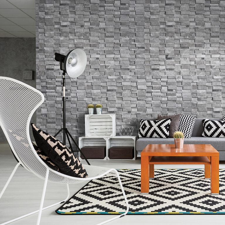 Niobe Gray 7x20 honed 3D marble ledger panel wall behind a sofa and patterned rug