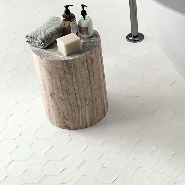 Close-up of a Switch 4x4-1/2 White hexagon tile floor with a wood stool