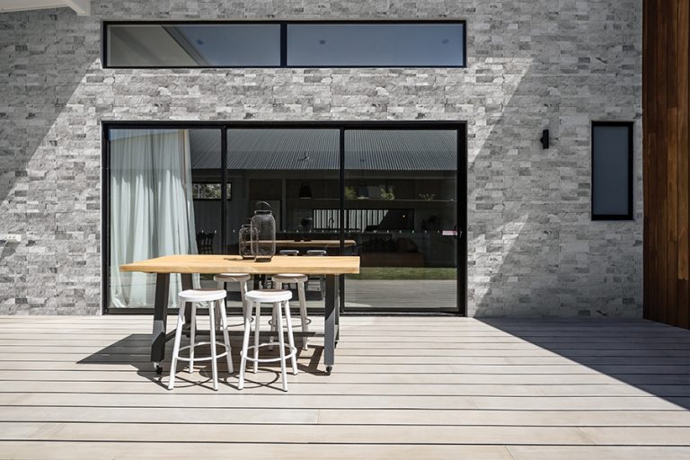 House exterior clad in Niobe Gray 7x20 splitface marble ledger panels beside a wood deck