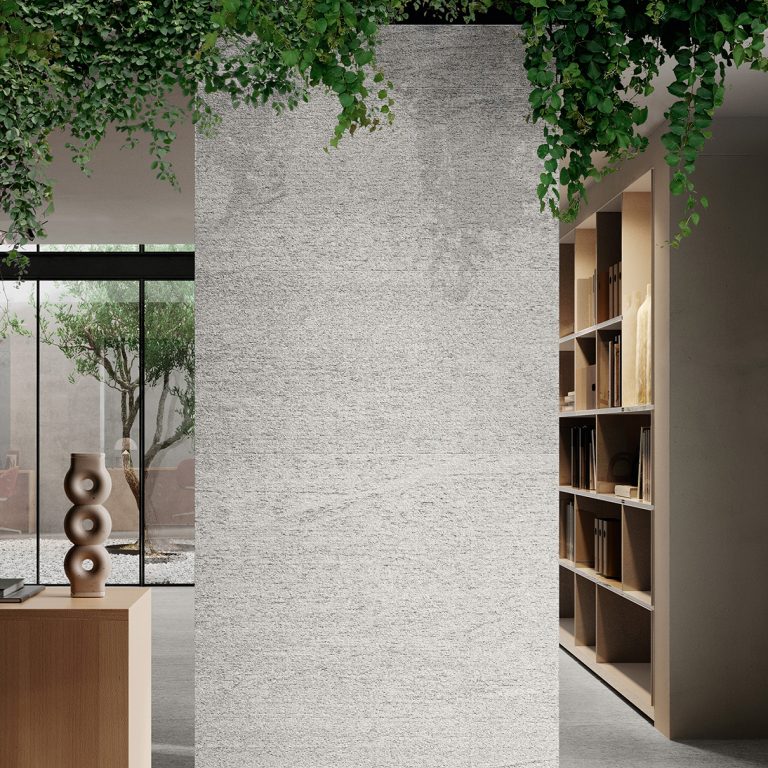 Upstone 24x48 Duke Bianco stone-look porcelain tile on a freestanding wall beside bookshelves