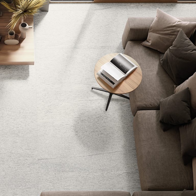Overhead view of an Upstone 24x48 Duke Bianco porcelain tile floor with a sofa and side table