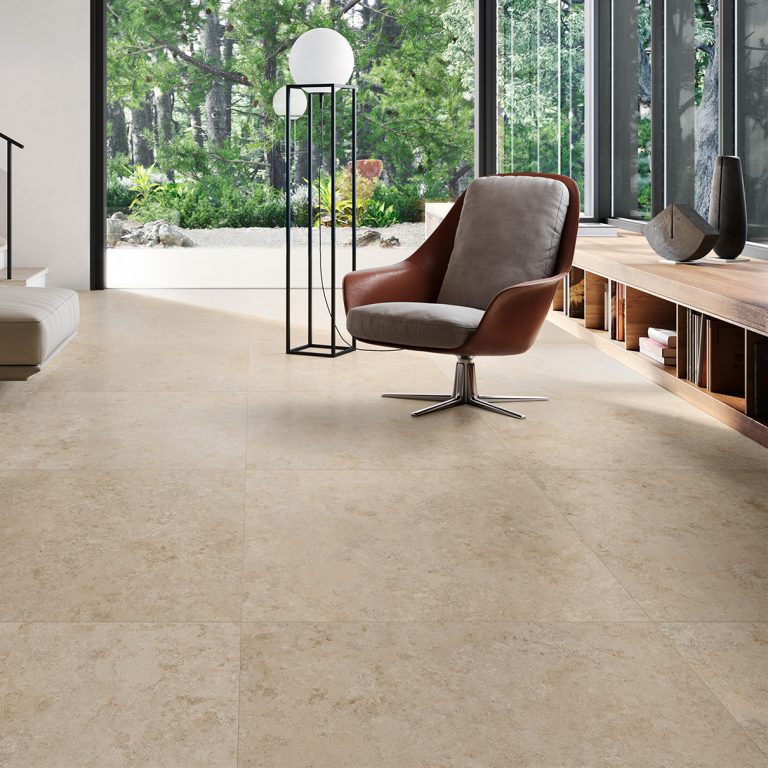 Upstone 24x48 Jura Beige stone-look porcelain tile floor with a lounge chair and garden view
