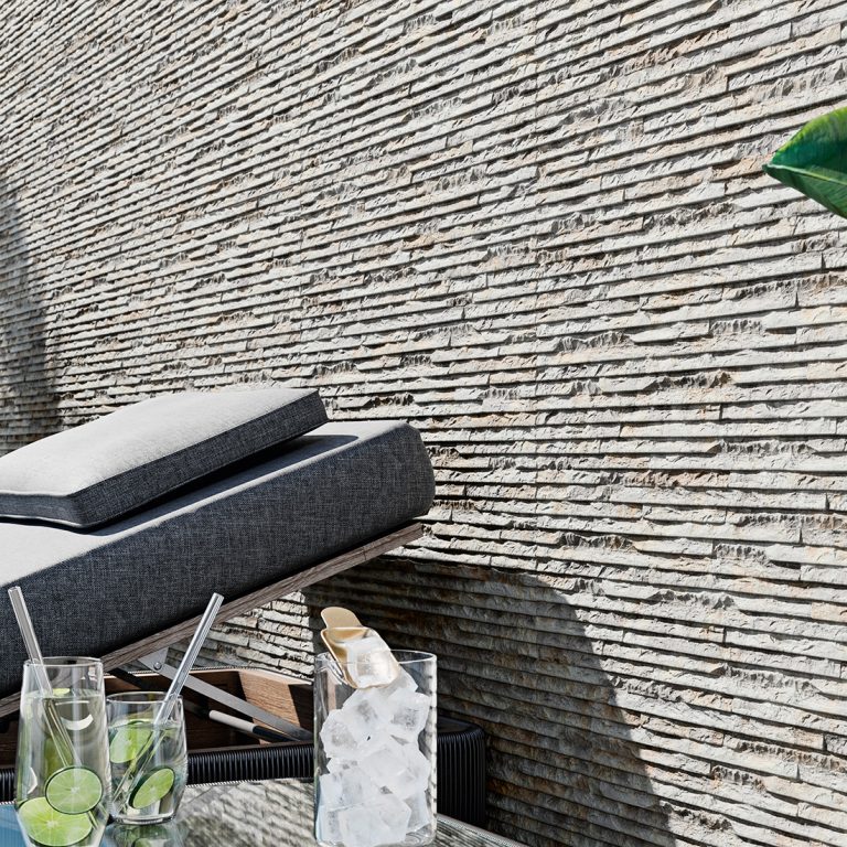 Patio wall in Iguazu 8x25 Gray raked stone-look wall panels behind outdoor lounge chairs