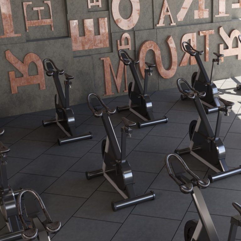 Fitness studio with a Eureka 12x24 black porcelain tile floor and spin bikes