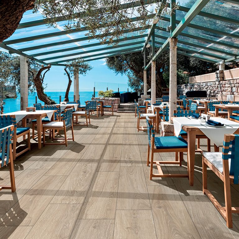 Seaside restaurant terrace with Baltic 12x48 Amber wood-look porcelain pavers under a pergola
