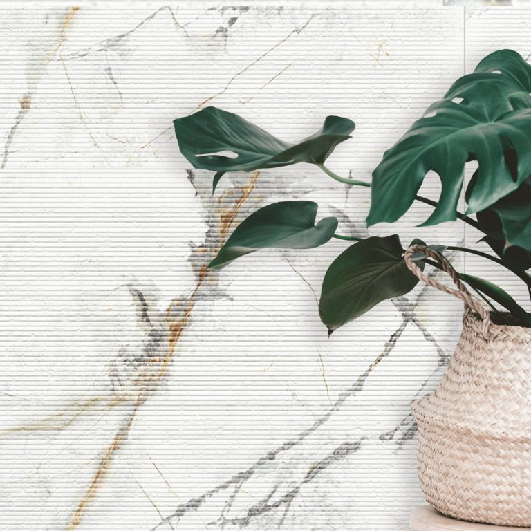 Invisible Gold 24x48 marble-look porcelain wall tile in a subtle raked finish with a potted monstera plant