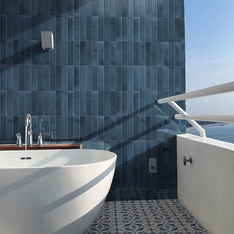 Bathroom with Posh 2-3/8x9-7/8 navy glossy brick tile walls, a freestanding tub and patterned floor tile