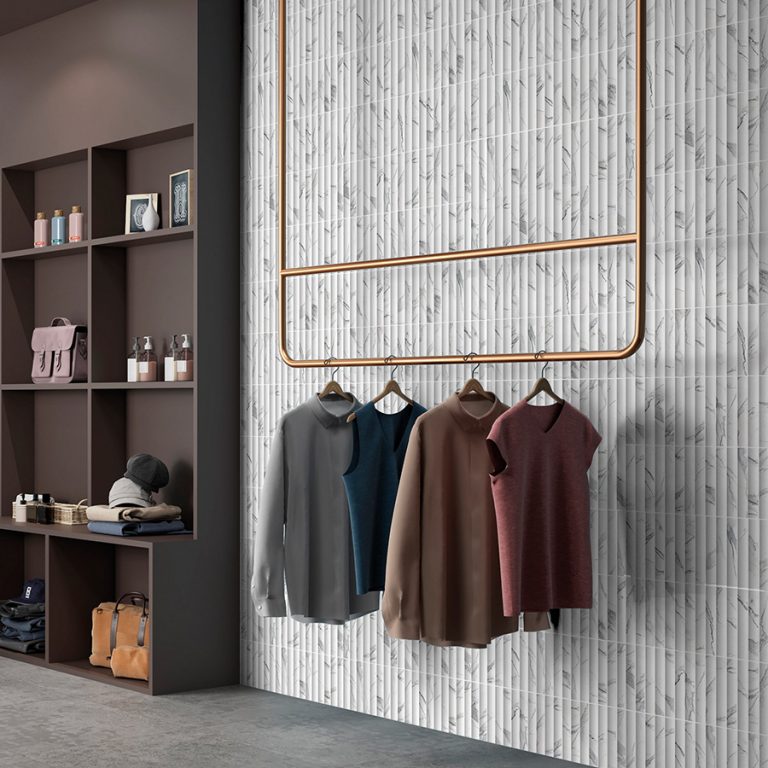Retail display wall in Arc 4-1/2x9 3D tile in Statuario with a copper clothing rail