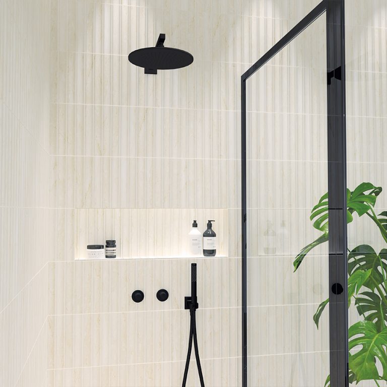 Walk-in shower with Arc 4-1/2x9 3D tile in Travertino Classico, a lit niche and black fixtures