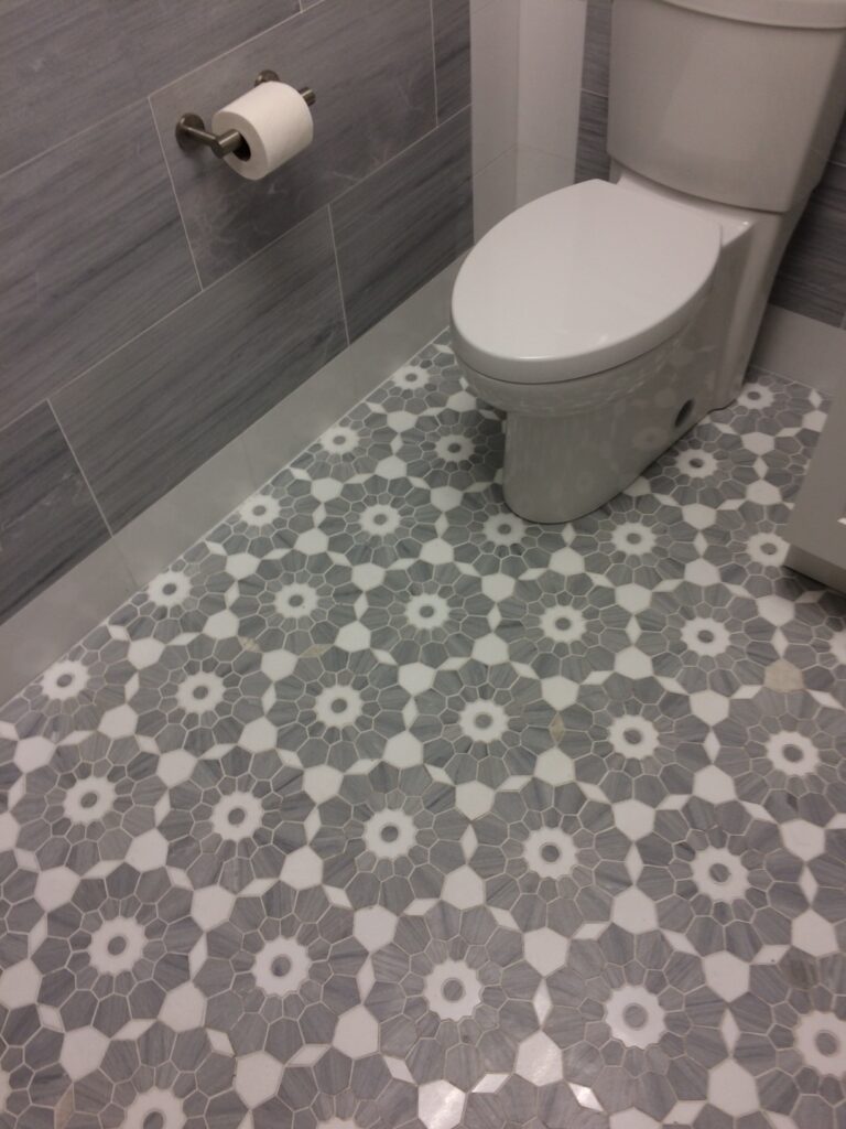 Bathroom floor in Bloom Merceene Vena and Thassos mosaic beside a toilet with Merceene Vena walls