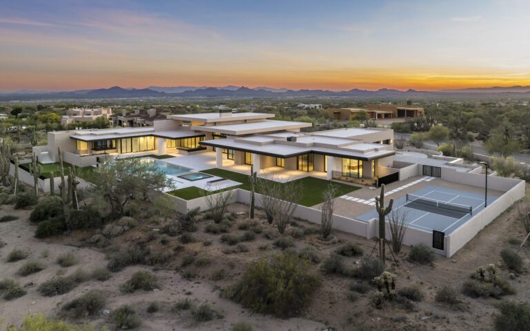 Aerial view at dusk of an Arizona desert home by Parolo Builders with a Silky Stone Light pool deck