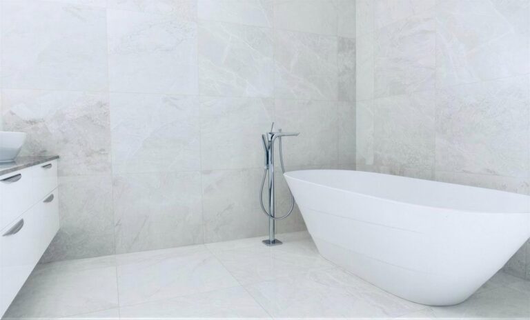 Bright bathroom with Vanilla 24x24 honed marble tile on the floor and walls and a freestanding white tub